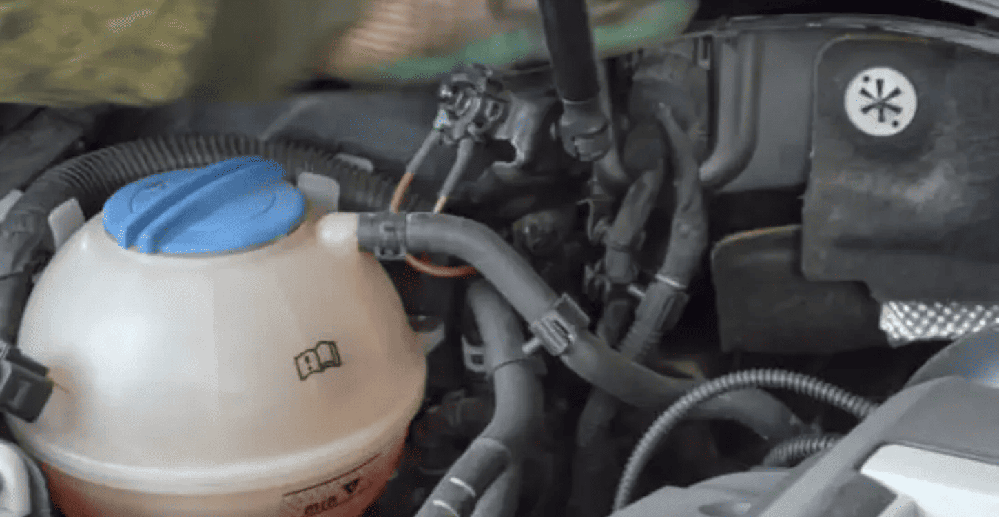 Coolant reservoir in a car engine bay showing fluid level that appears normal despite underlying cooling system issues